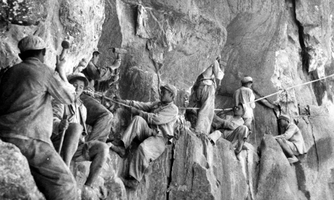 1954年，修筑康藏公路的解放軍戰(zhàn)士們?cè)谂瓋砂兜膽已露副谏媳偕街?。新華社稿 李萬(wàn)春、張加里攝